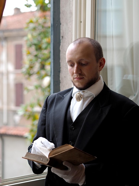 Foto uomo che indossa un vestito mentre legge un libro a casa