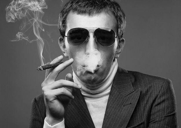 남자 선글라스를 착용 하 고 담배를 흡연입니다.