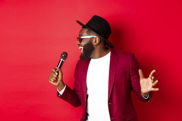 Man wearing sunglasses standing against red background