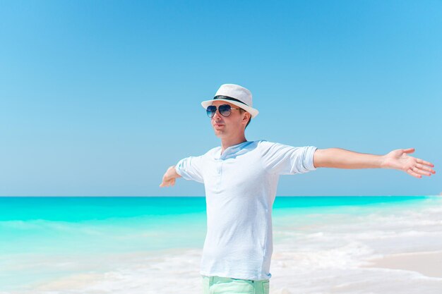 Man wearing sunglasses standing on beach against clear sky