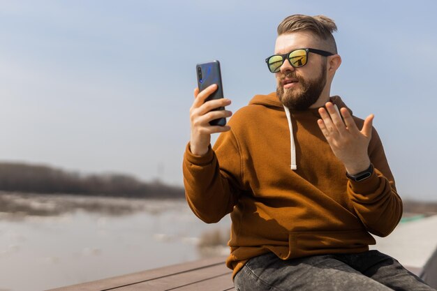 Photo man wearing sunglasses talking on video call against sky
