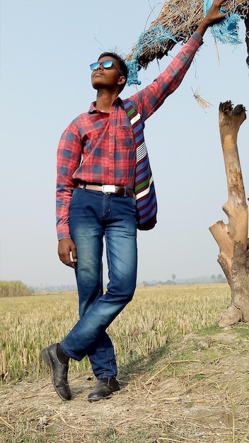 Photo man wearing sunglasses while standing on grass against clear sky