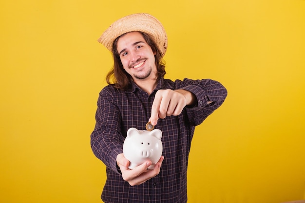 Man wearing typical clothes for party Junina Holding coin and piggy bank Economy and finance concept private retirement