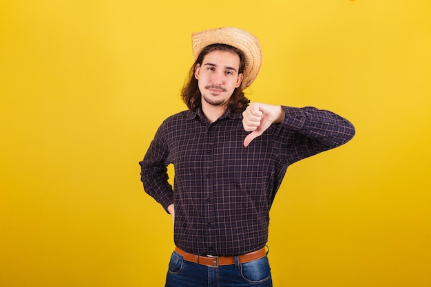 Man wearing typical clothes for party Junina Thumb down disapproved disapproval negative
