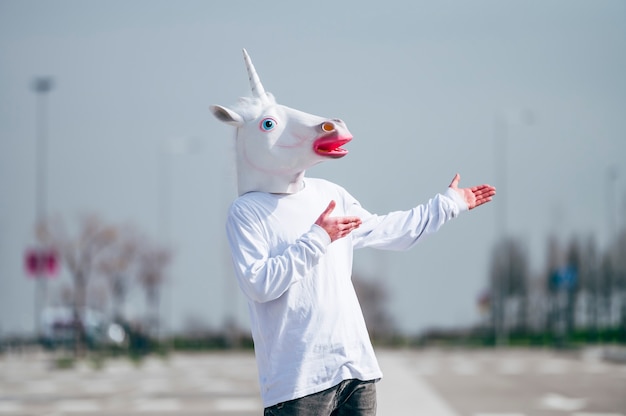 Photo man wearing unicorn mask gesturing to his left side