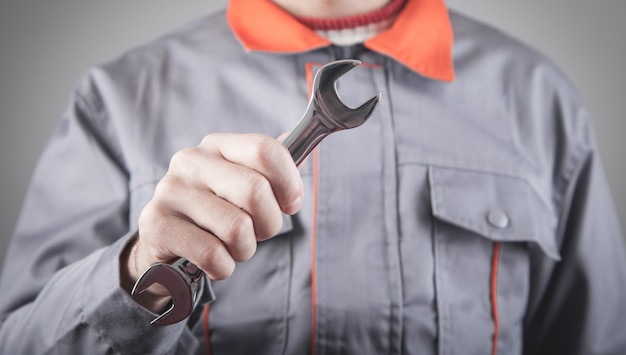 Man wearing a uniform holding a wrench.