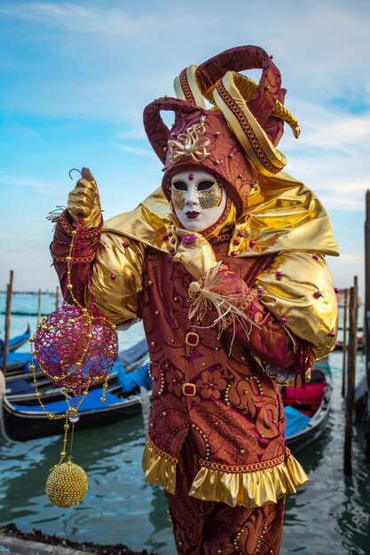 Foto uomo che indossa una maschera veneziana mentre si trova sul mare contro il cielo