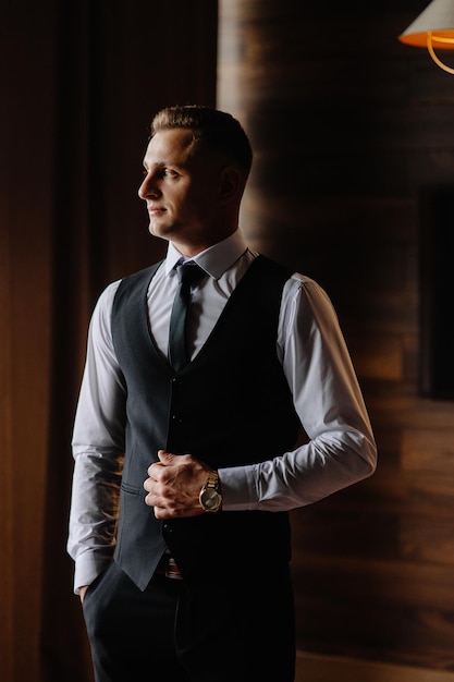 a man wearing a vest and tie stands in front of a wall