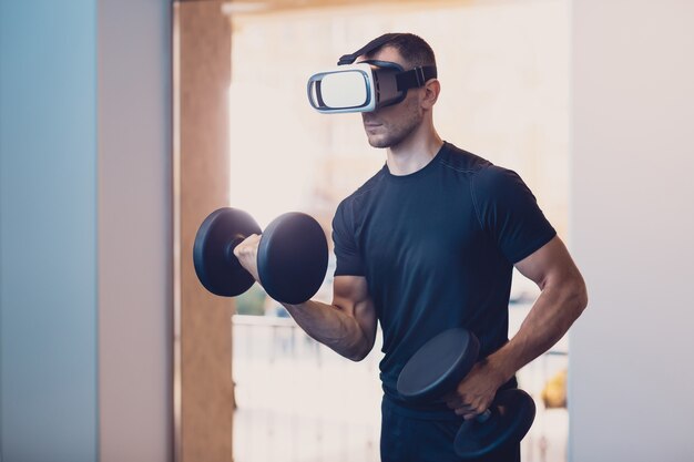 Man wearing virtual reality glasses with dumbbells