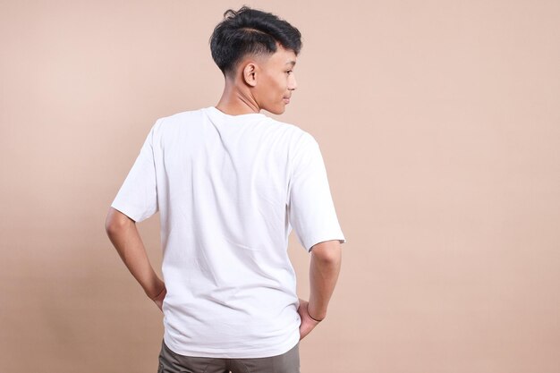 Man wearing white blank tshirt and showing the back side over beige background