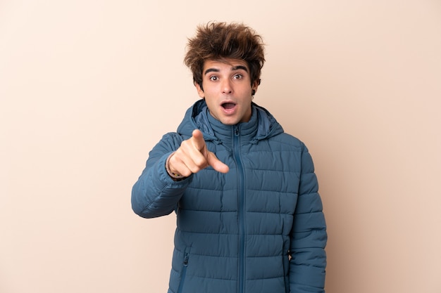 Man wearing winter jacket surprised and pointing front