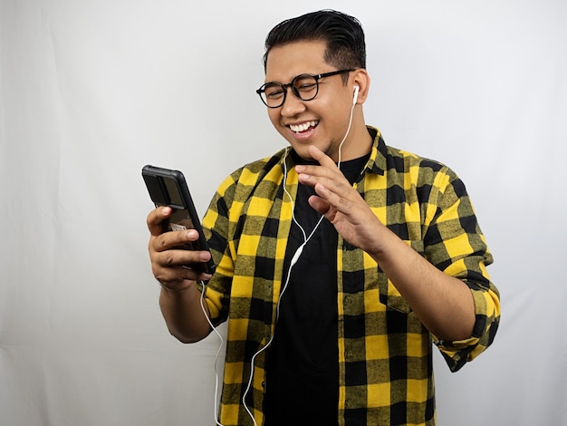 a man wearing a yellow plaid shirt is listening to a mp3 player.