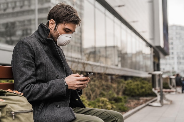 Man wears mask to prevent virus and for protection while using mobile phone