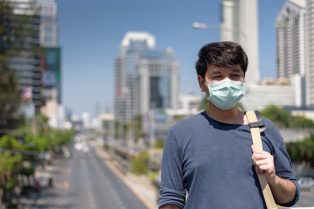 man wears surgical face mask carrying shoulder bag