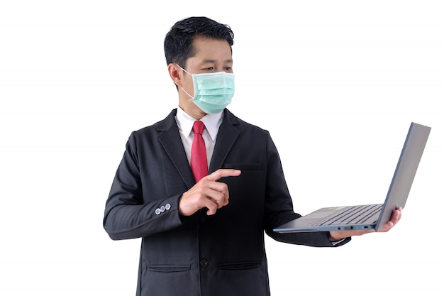 Фото Человек носит хирургическую маску и держит ноутбук