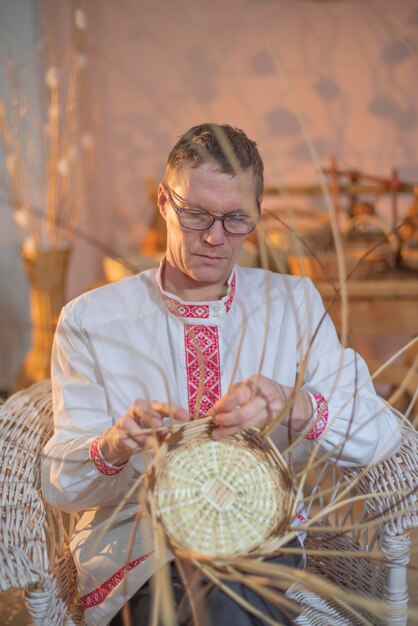 Фото Мужчина плетет корзины из ивовых веток