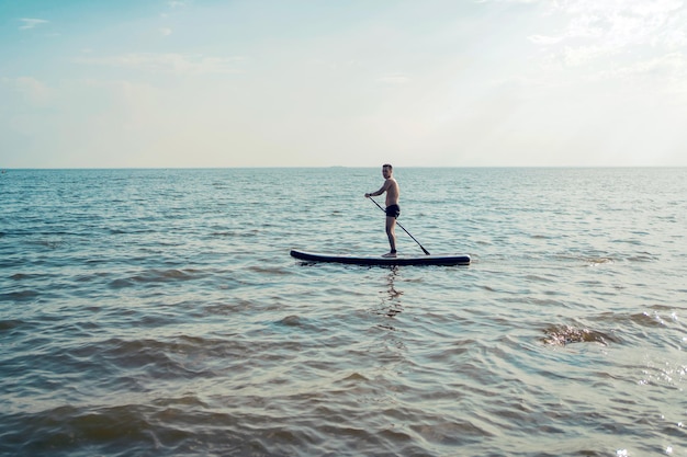 A man on a weekend vacation riding a sup board on the sea