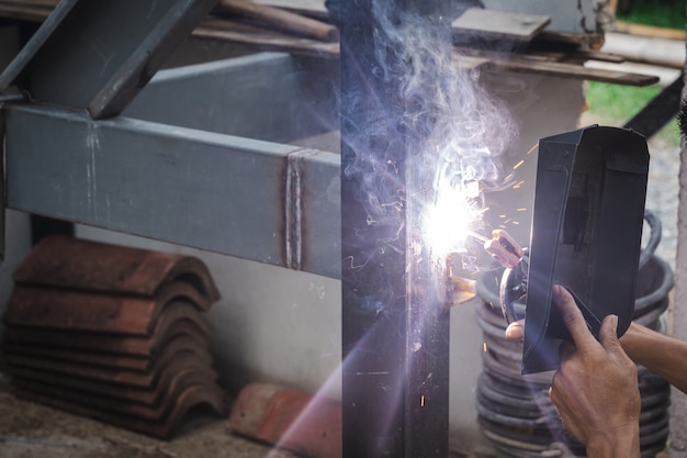 Man welder doing a metal staircase structure in a residential building using a welding machine.