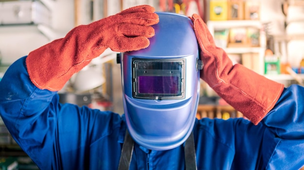 Un uomo saldatore che mette il casco per proteggere gli occhi lavoratore che indossa abiti speciali