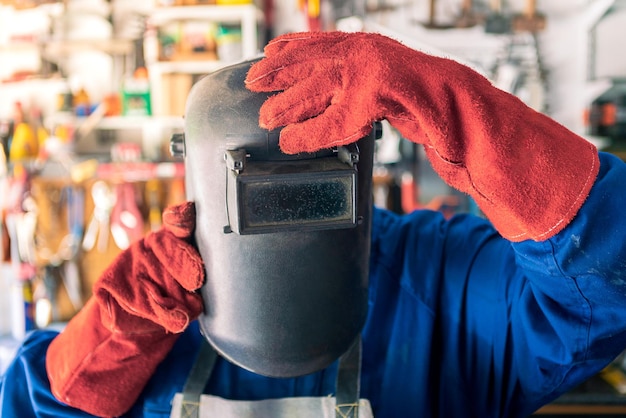 Un uomo saldatore che mette il casco per proteggere gli occhi lavoratore che indossa abiti speciali