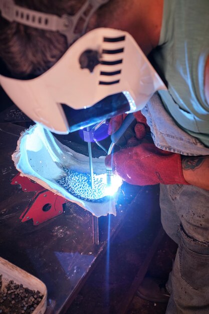 Man welding metal pieces in factory