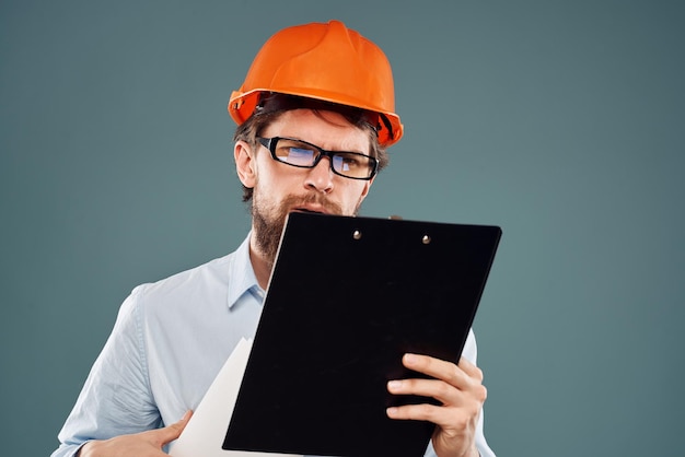 Man werknemer met documenten in handen met een bril oranje helm veiligheidsprofessionele foto van hoge kwaliteit