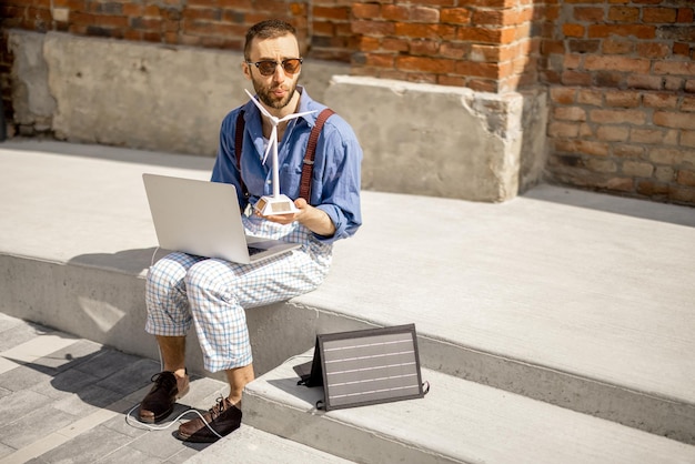 Man werkt en laadt laptop op vanaf draagbaar zonnepaneel