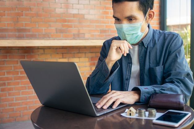 Man werkt freelance in café door laptopcomputer, mensen dragen gezichtsmasker om covid19 te beschermen