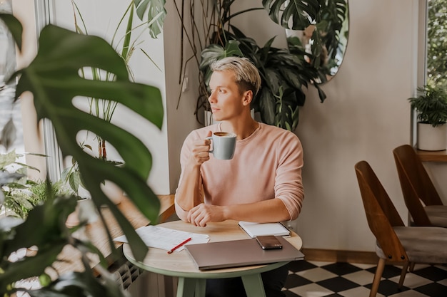 Man werkt op de werkvloer met documenten en drinkt koffie in een ecocafé met planten