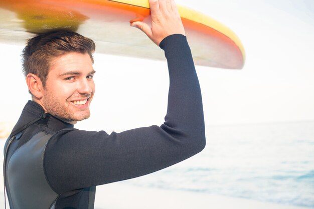 Man in wetsuit with a surfboard on a sunny day