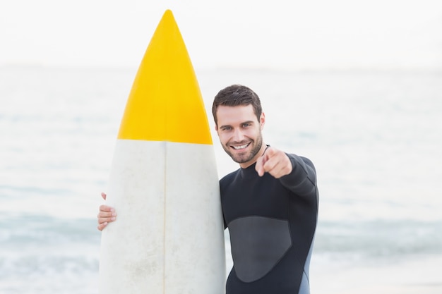 Человек в гидрокостюме с доской для серфинга в солнечный день