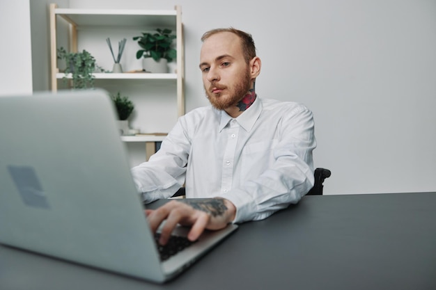 A man in a wheelchair a businessman with tattoos in the office works at a laptop integration into society the concept of working a person with disabilities freedom from social frameworks