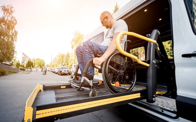 A man in a wheelchair on a lift of a specialized vehicle for people with disabilities.