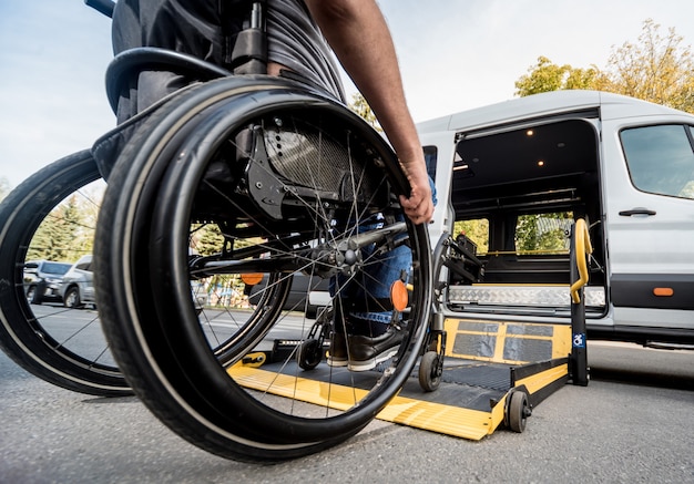 A man in a wheelchair moves to the lift of a specialized vehicle