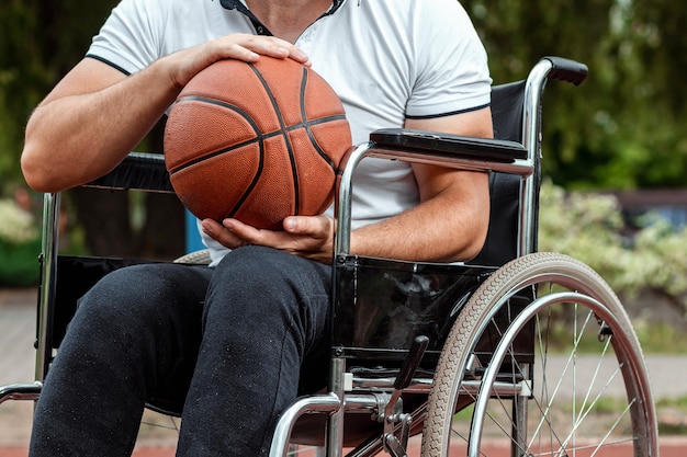 A man in a wheelchair plays basketball on the sports ground.\
the concept of a disabled person, a fulfilling life, a person with\
a disability, fitness, activity, cheerfulness