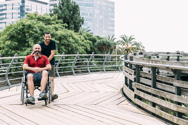 Man in wheelchair walks with a friend in the park