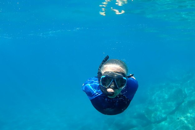 地中海のチンクエテッレ・モンテロッソでダイビングしながら、水中の太陽の光に照らされた透き通った海岸で自由に泳ぐ男性