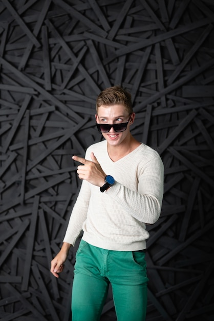 Man in a white blouse posing against a black wall