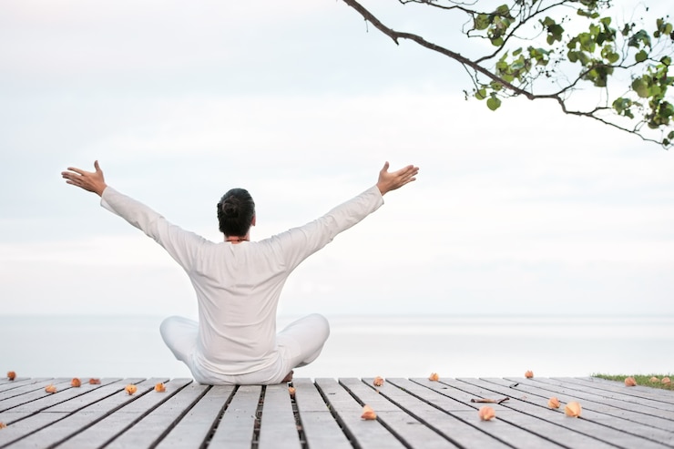 Photo man in white clothes meditating yoga on wooden pier