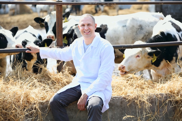 Man in a white coat on the cow farm