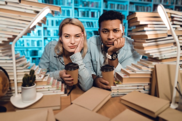 Man and white girl sitting at table surrounded by books.