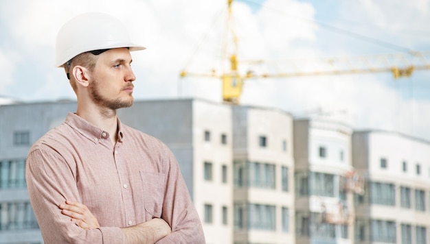 A man in a white helmet in front of a building under construction