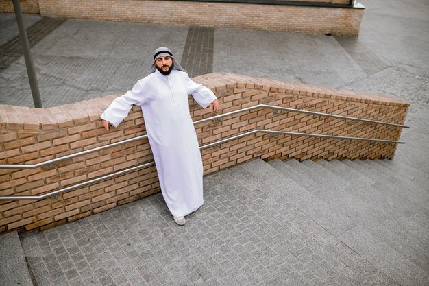 Man in white long thobe on a brick wall background