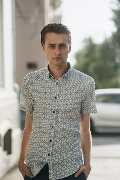 A man in a white plaid shirt and blue trousers poses for advertising men's clothing. Shooting for men's clothing store