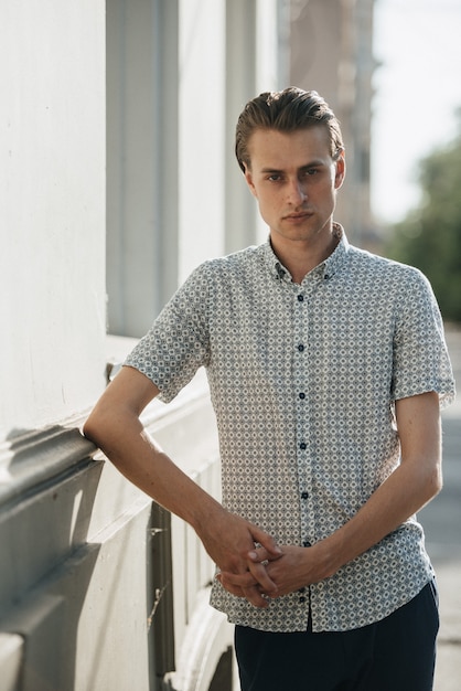 A man in a white plaid shirt and blue trousers poses for advertising men's clothing. Shooting for men's clothing store