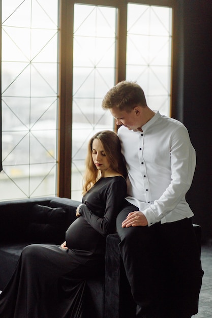 Uomo in camicia bianca e donna in abito nero foto di gravidanza