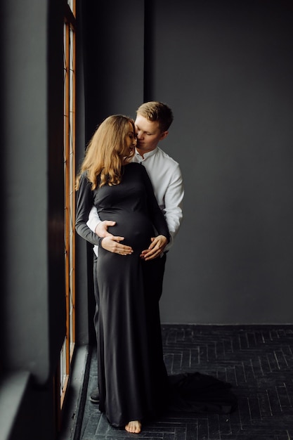 Uomo in camicia bianca e donna in abito nero foto di gravidanza