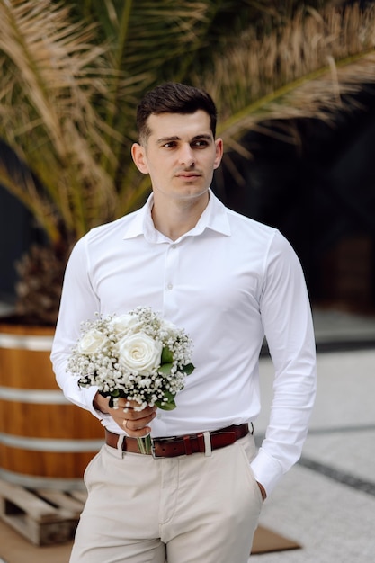 A man in a white shirt holds a bouquet of flowers.