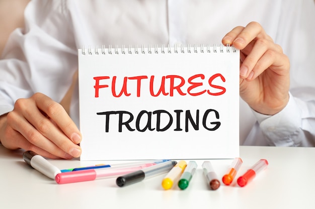 Photo a man in a white shirt holds a piece of paper with the text: futures trading