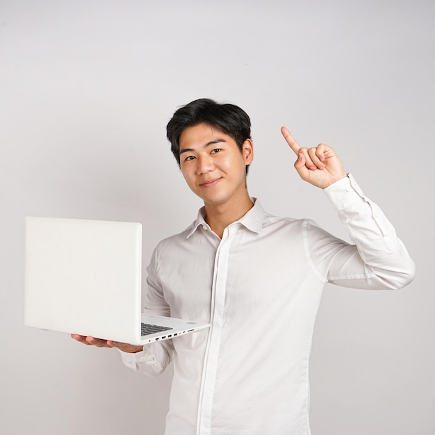 Photo a man in a white shirt holds up a laptop with the index finger pointing up.